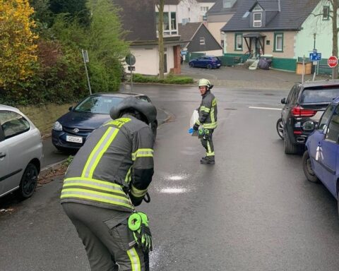 Feuerwehrleute streuen Bindemittel auf einer Ölspur zur Gefahrenabwehr nach einem Unfall.