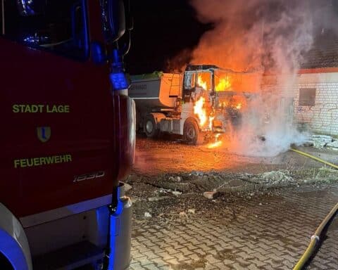 Brennender LKW, Feuerwehr im Einsatz, Brandbekämpfung mit Schaum, Nachtaufnahme in urbaner Umgebung.