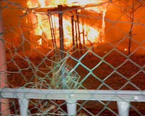 Feuerwehr löscht brennende Gartenlaube in Remscheid; Einsatzkräfte und brennende Struktur sichtbar.