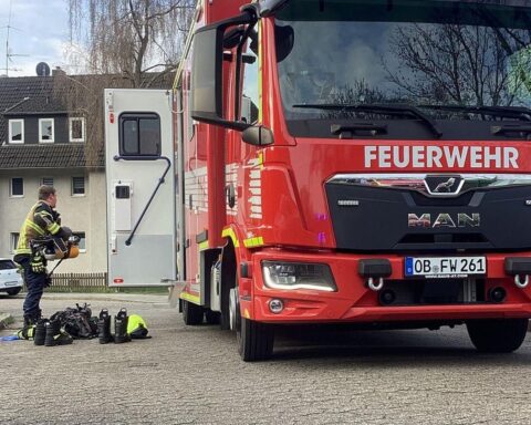 Feuerwehr löscht Dachbrand, rettet Katzen; Einsatzort mit Rauch und Einsatzkräften abgebildet.