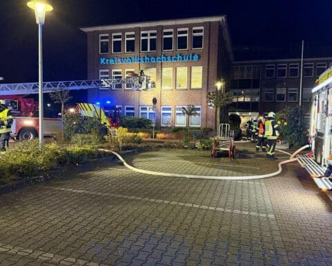 Einsatzkräfte der Feuerwehr bei Großübung, Brandbekämpfung und Personenrettung an Schule.