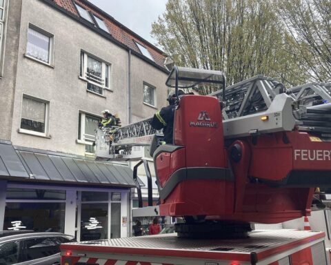 Frau wird von Feuerwehr nach Wohnungsbrand schwer verletzt gerettet, Einsatzkräfte arbeiten vor Ort.