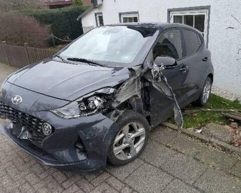Zwei beschädigte Autos an Unfallstelle, Polizei und Krankenwagen im Hintergrund, verletzte Fahrer.