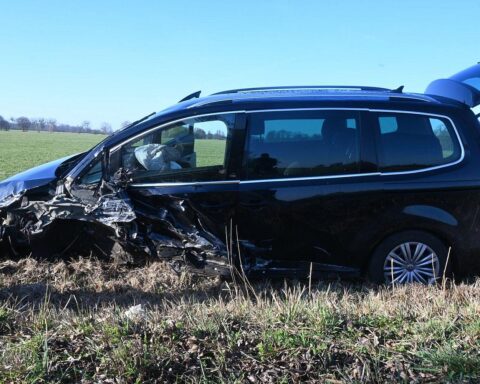 Zwei beschädigte Autos auf einem Feld nach schwerem Unfall, Polizei und Rettungsdienst vor Ort.