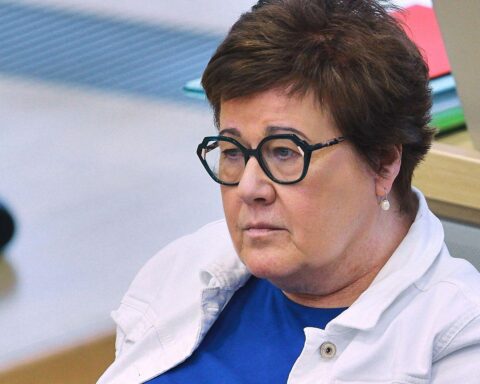 Frau in Anzug spricht vor Publikum, Dokumente in der Hand, Gleichstellung symbolisiert Fortschritt.