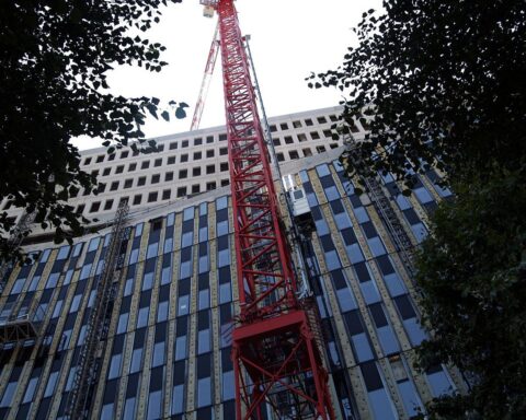Baustelle mit Wohnungsbau-Symbolik, umringt von politischen Debatten über sozialen Wohnraum.