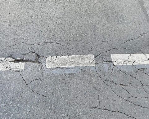 Rissige Fahrbahn mit Schlaglöchern, symbolisiert Frostschäden und notwendige Straßenreparaturen in Hessen.