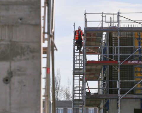 Bauarbeiter auf Baustelle, optimistische Stimmung im Wohnungsbau, aber Auftragslage bleibt herausfordernd.