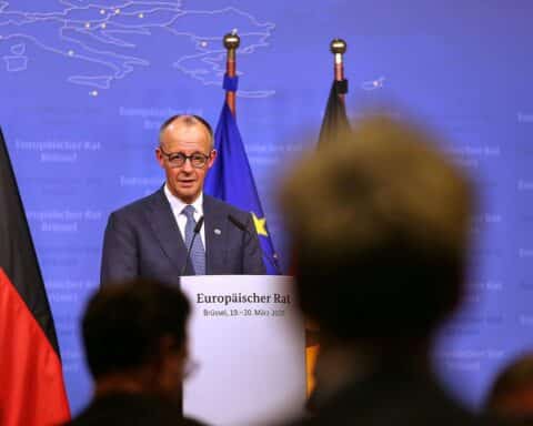 Friedrich Merz spricht auf einer politischen Veranstaltung, im Hintergrund das Union-Logo und Wählerumfrage.