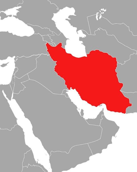 Iranische Flagge hinter einem Politiker, der Frieden und Zusammenarbeit mit Nachbarn symbolisiert.