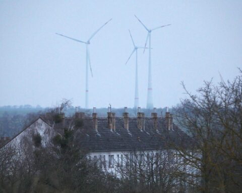 Ein Mehrfamilienhaus mit Windrädern symbolisiert nachhaltige Energie und Mieterschutz im Gebäudevermietungsrecht.