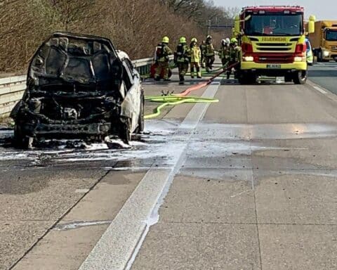 Pkw-Brand auf Autobahn, Feuerwehr im Einsatz, Rauch und gesperrte Fahrspur, rettendes Eingreifen.
