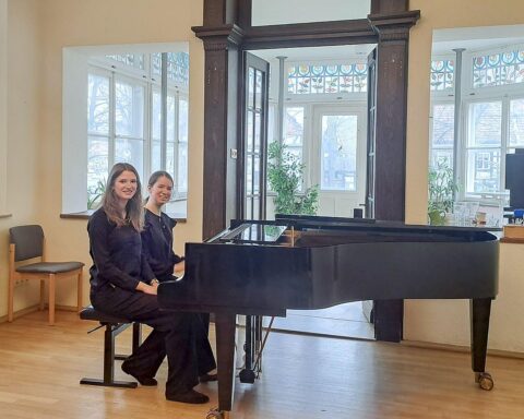 Zwei talentierte Pianistinnen des Klavierduos am Wettbewerb, umgeben von Tasten und Musiknoten.