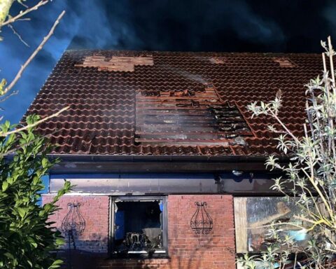 Brand eines Wohnhauses: Feuerwehr löscht, Dach abgedeckt, Bewohner verletzt, Polizei ermittelt.