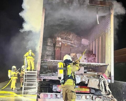 Brennender Lastwagen auf Autobahn, Feuerwehr bei aufwändigen Löscharbeiten, Paketladung im Fokus.