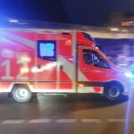 Rettungswagen an Autobahn, Unfallopfer wird behandelt, mehrere Fahrzeuge betroffen, Polizeieinsatz sichtbar.