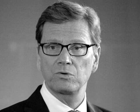 Porträt von Guido Westerwelle, umgeben von Kerzen und Blumen zur Gedenkstunde.