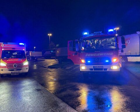 Einsatzkräfte helfen bei medizinischem Notfall auf Rastplatz, sichern Verkehr für Sicherheit.