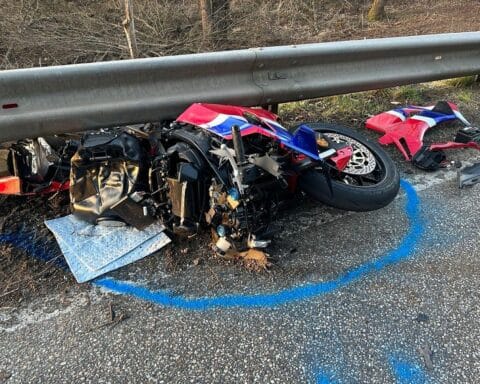 Zerstörtes Motorrad nach schwerem Unfall, Feuerwehr und Rettungshubschrauber im Einsatz.