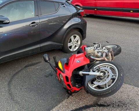 Auto und Motorrad nach Unfall, flüchtender Fahrer unter Drogen, Polizeieinsatz im Hintergrund.