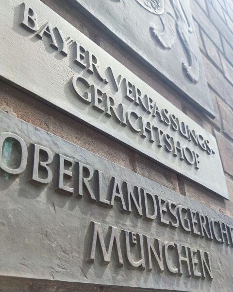 Gerichtssaal mit Richterin, Sicherheitskontrollen und Anwälten während eines Terrorprozess.
