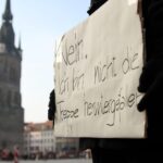 Demonstrantin mit Protestschild, die gegen Gewalt an Frauen und für Unterstützung kämpft.