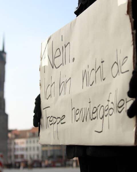 Demonstrantin mit Protestschild, die gegen Gewalt an Frauen und für Unterstützung kämpft.