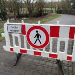 Hochwasser-Warnungsschild in Niedersachsen, symbolisiert Schutzmaßnahmen gegen Klimafolgen und Deichbauprojekte.