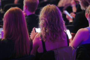 Junge Menschen benutzen Smartphones und interagieren mit sozialen Medien in einem lebhaften Umfeld.