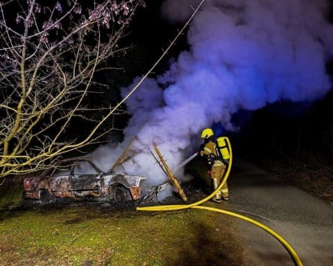 Feuerwehrlöscharbeiten an einem brennenden Pkw in Detmold-Pivitsheide bei Nacht.