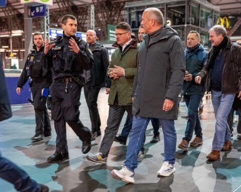 Zwei Politiker in Polizei-Kleidung, während sie eine große Polizeikontrolle im Frankfurter Bahnhofsviertel beobachten.