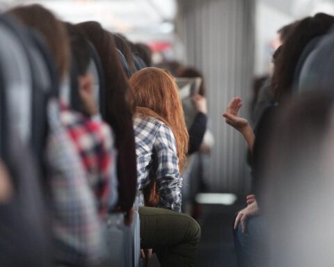 Rothaarige Frau im Flugzeug symbolisiert günstigen Luftverkehr und kommende Steuerentlastung für Passagiere.