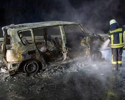 PKW-Brand auf Autobahn mit Feuerwehr und beschädigtem Fahrzeug, Rettungskräfte im Einsatz.