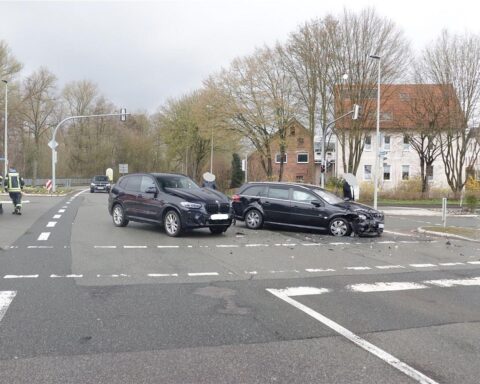 Unfallstelle mit beschädigten Fahrzeugen, Polizei und Rettungsdienst vor Ort. Leicht verletzte Autofahrerin.