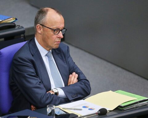 Friedrich Merz spricht in Berlin, umgeben von politischen Beratern und Journalisten.