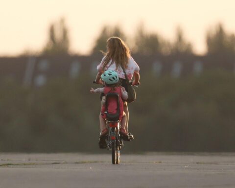 Frau und Kind üben Verkehrssicherheit in einer mobilen Verkehrsschule, um Unfälle zu vermeiden.