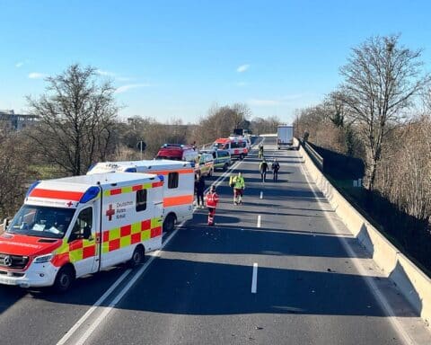 Rettungswagen und ein Hubschrauber am Unfallort, Einsatzkräfte helfen verletzten Personen.