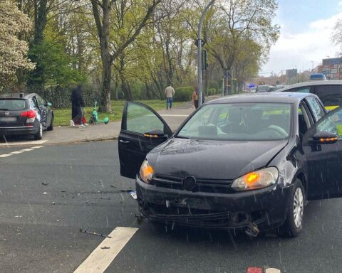 Verkehrsunfall mit zwei beschädigten PKW, Polizei vor Ort, schwerverletzte Person, Chaos auf der Straße.
