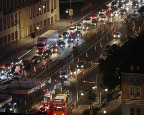 Pendler im Feierabendverkehr, umgeben von Tankstellen und hohen Spritpreisen, zeigen wirtschaftliche Herausforderungen.