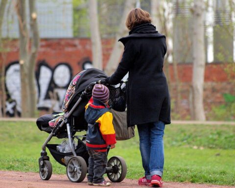 Mutter mit Kinderwagen im Park, Symbol für Familie und Vereinbarkeit von Beruf und Kindererziehung.