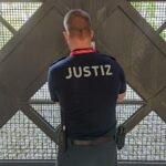 Wachmeister öffnet Gefängnistor, Symbol für vorzeitige Entlassungen in Deutschland.