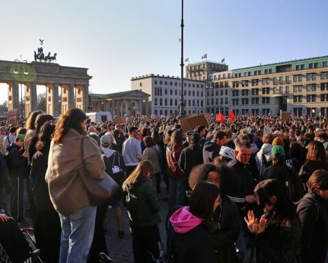 Demonstranten am Brandenburger Tor zeigen Schilder gegen sexualisierte digitale Gewalt und für Solidarität.