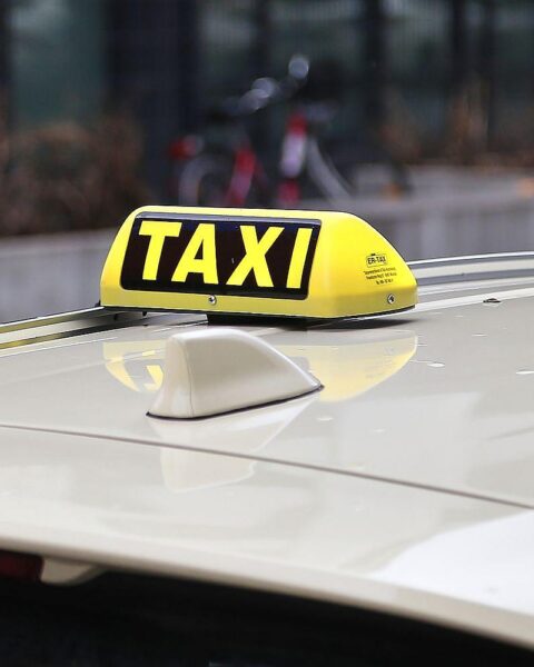 Ein Taxi auf der Straße, umgeben von Polizeifahrzeugen und einem Hubschrauber.