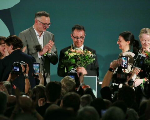 Cem Özdemir feiert Wahlsieg, umgeben von grünen Symbolen und positiven Botschaften zur Politik.