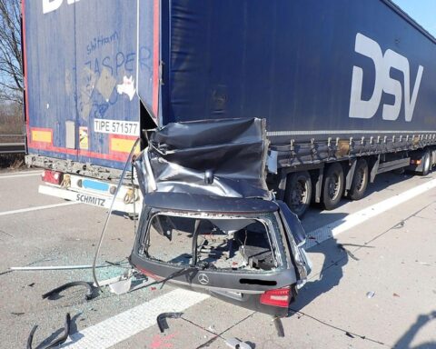 Schwere Verkehrsunfallstelle mit abgerissenen Fahrzeugteilen und Unfallfahrzeug auf Autobahn.
