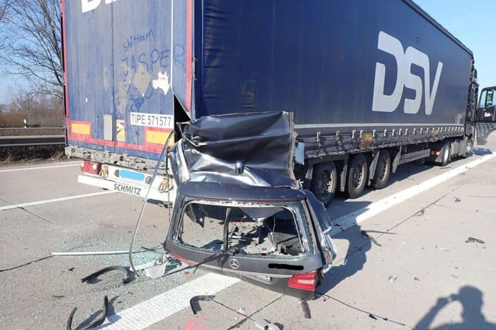 Schwere Verkehrsunfallstelle mit abgerissenen Fahrzeugteilen und Unfallfahrzeug auf Autobahn.