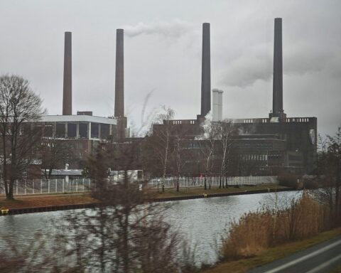 Volkswagen-Logo mit Grafiken zu Gewinnrückgang und Herausforderungen im Automobilsektor.