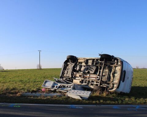Ein umgekipptes Van-Fahrzeug nach einem Verkehrsunfall, Rettungskräfte im Einsatz, beschädigter Stromkasten.