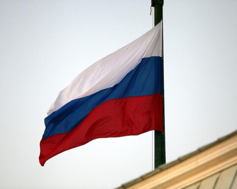 Russische Fahne vor Militär- und Nachrichtenkontext, symbolisiert Bedrohung durch Spionageaktivitäten.