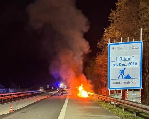 Brennender Pkw auf Autobahn, Feuerwehr im Einsatz mit Einsatzfahrzeugen und Absperrung.